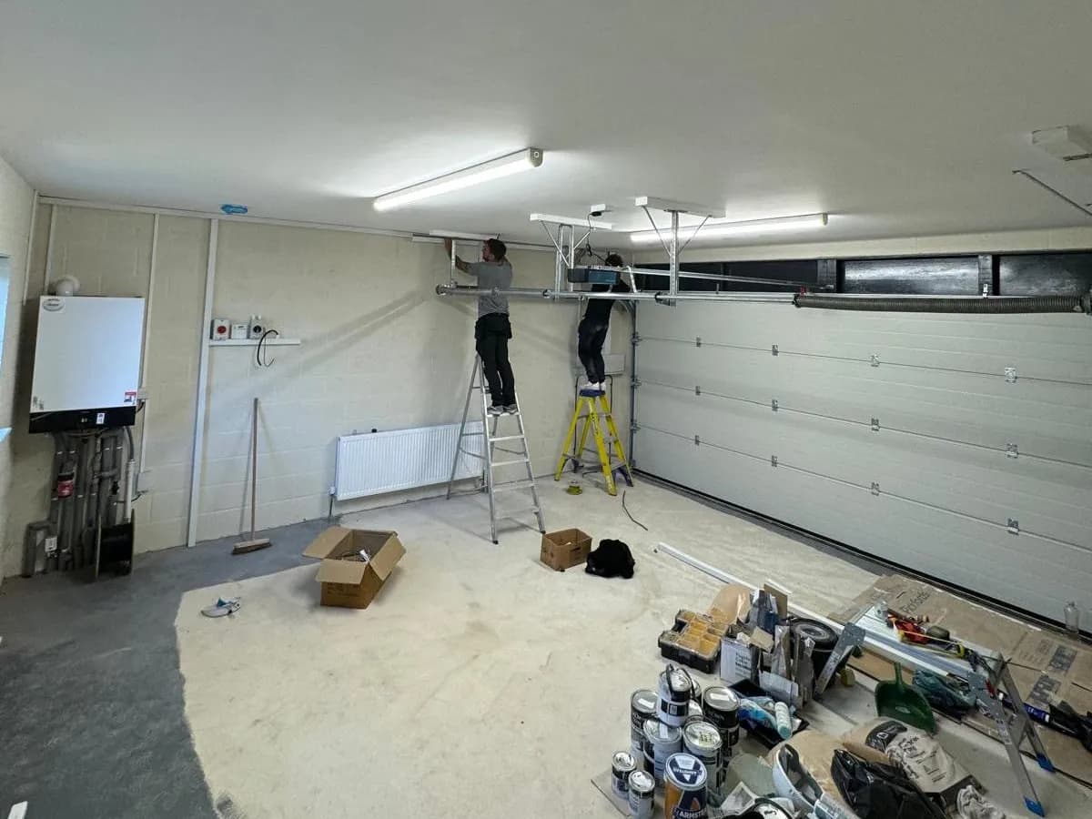 Two people on stepladders working at the ceiling of a domestic garage during a fit out